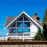 A modern A-frame house with large windows against a clear blue sky, showcasing contemporary architecture.