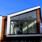 Contemporary house in Poole, UK featuring a sleek design with large glass windows and wood paneling.