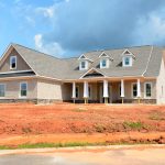 Brick modern family home under bright sky, showcasing new construction and architectural style.
