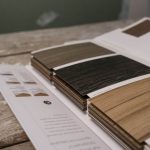 Collection of wood veneer samples displayed on a rustic wooden table indoors.