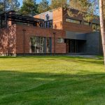 Contemporary house with large windows surrounded by lush greenery and trees.