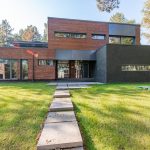 Contemporary building with brick and glass facade, set amidst green lawn.
