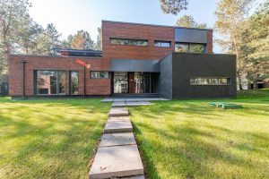 Contemporary building with brick and glass facade, set amidst green lawn.