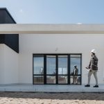 Architect with hard hat evaluating modern house exterior. Ideal for construction and architecture themes.