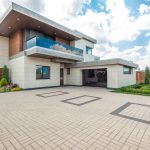 Elegant modern house exterior with lush greenery and ample driveway space.